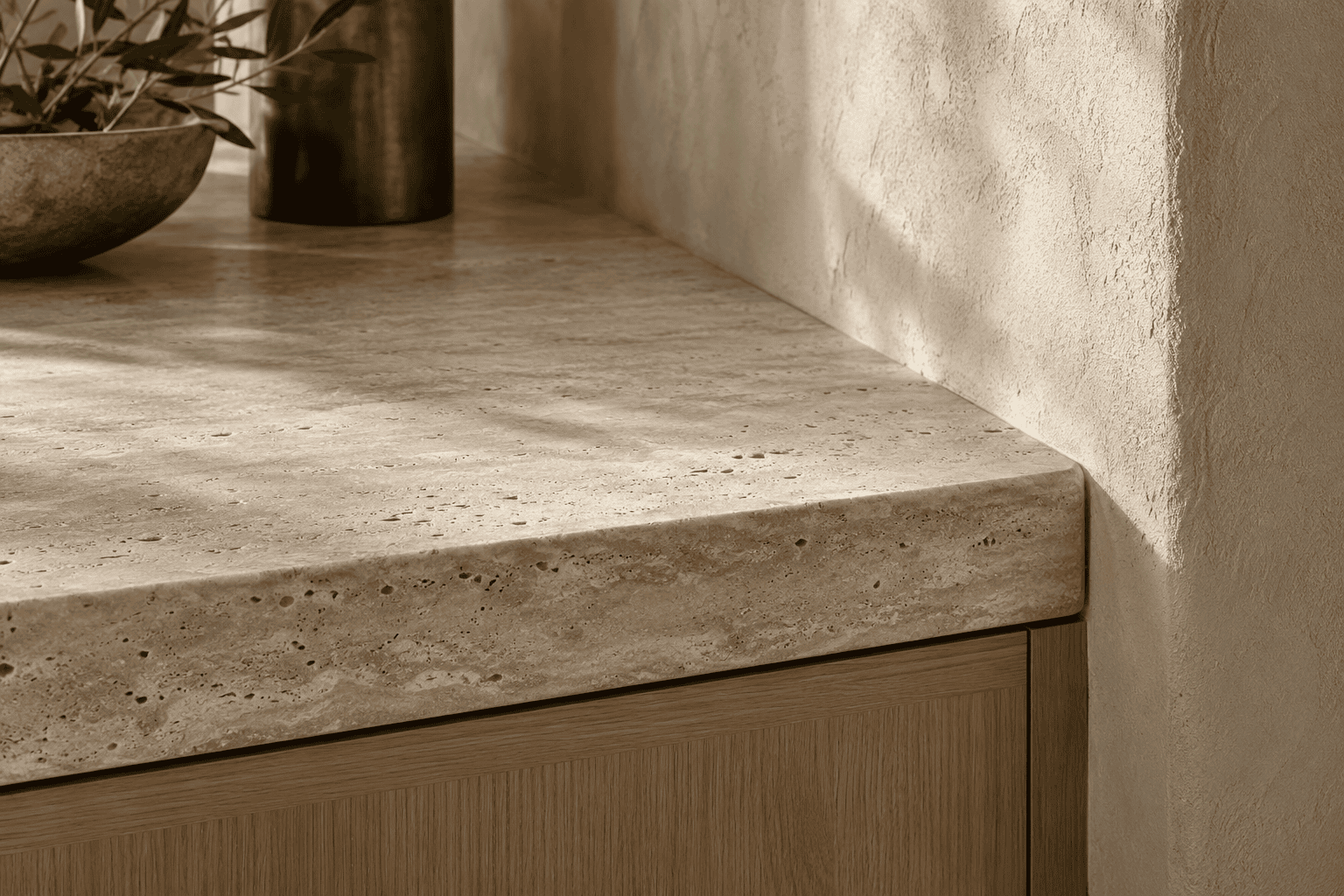 Detalle de encimera de piedra porosa junto a pared texturizada y mueble de roble